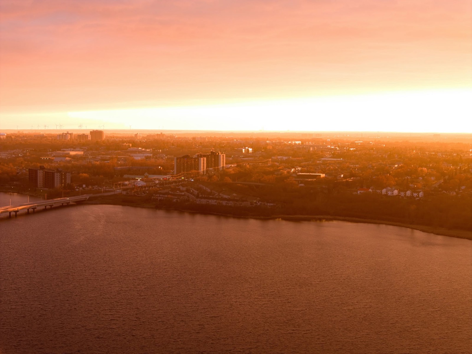 The city and a bridge seen across the water in low golden light.