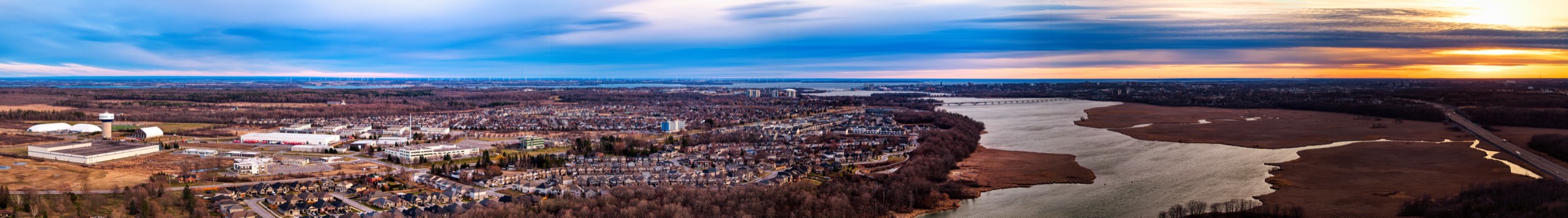 Panorama of Kingston at dusk, houses along the river and marsh.