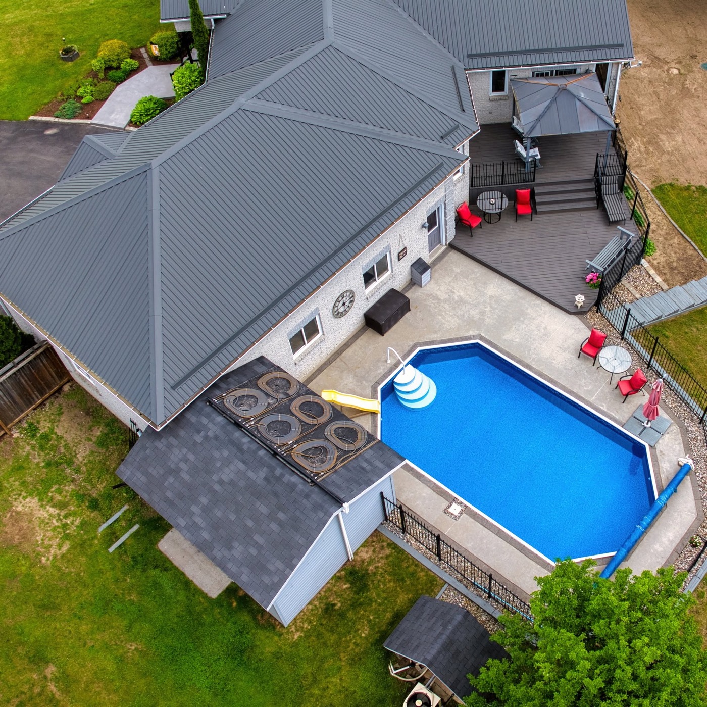 Overhead view of a house, a blue pool, and a deck with red chairs.